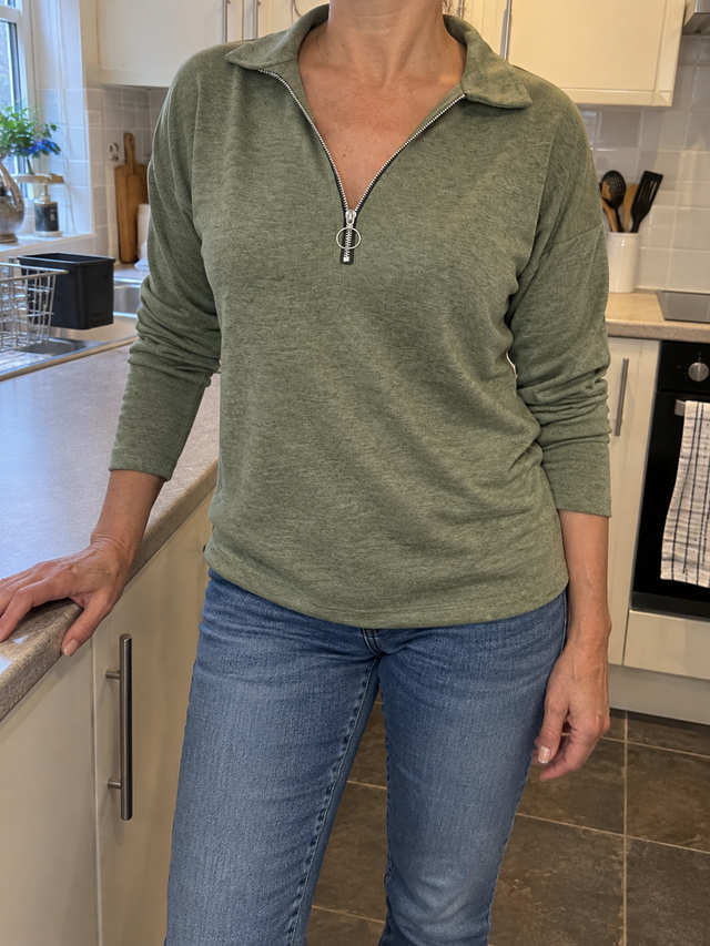 Green zip-neck jumper worn in a kitchen
